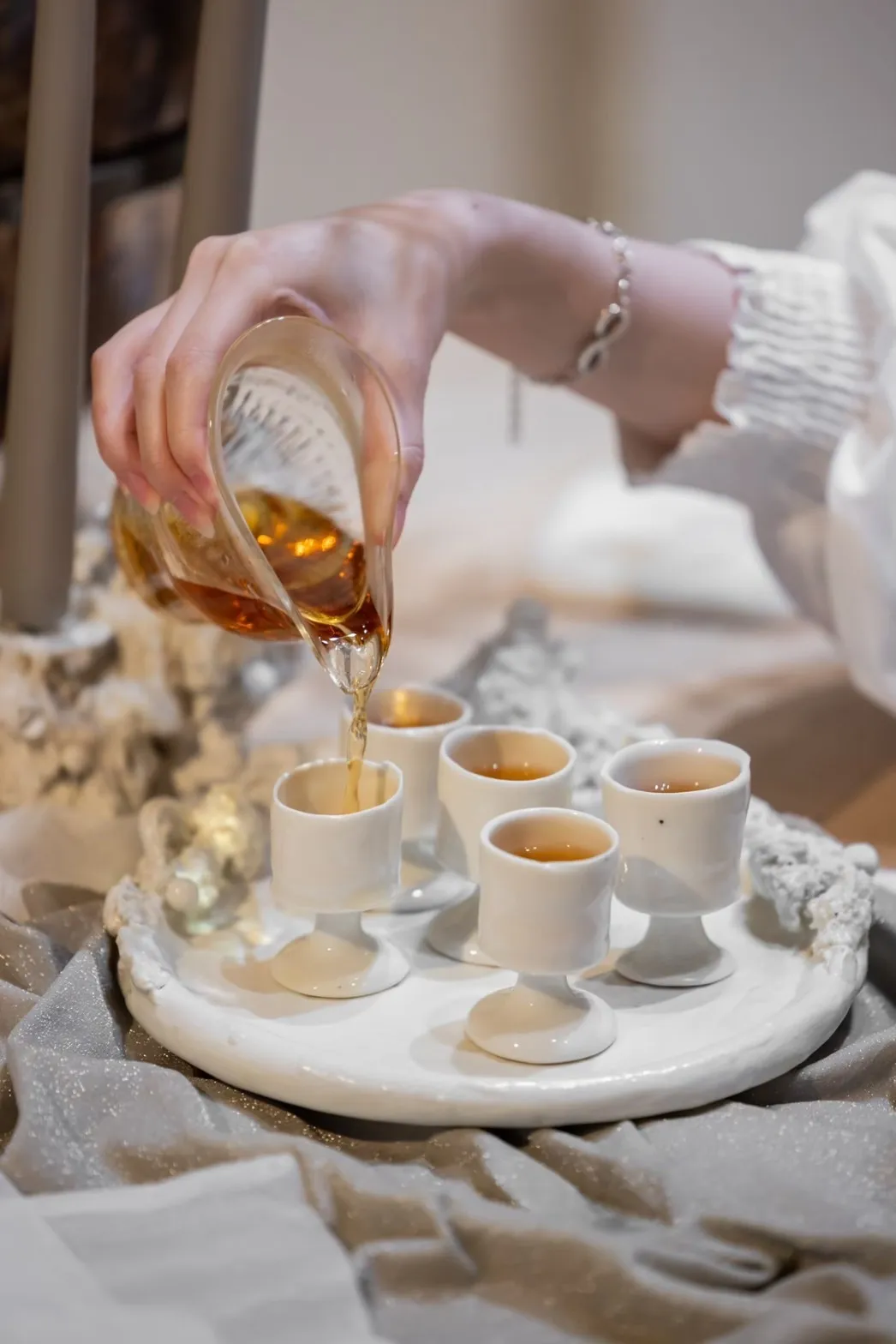 A hand pouring tea into a tea cup