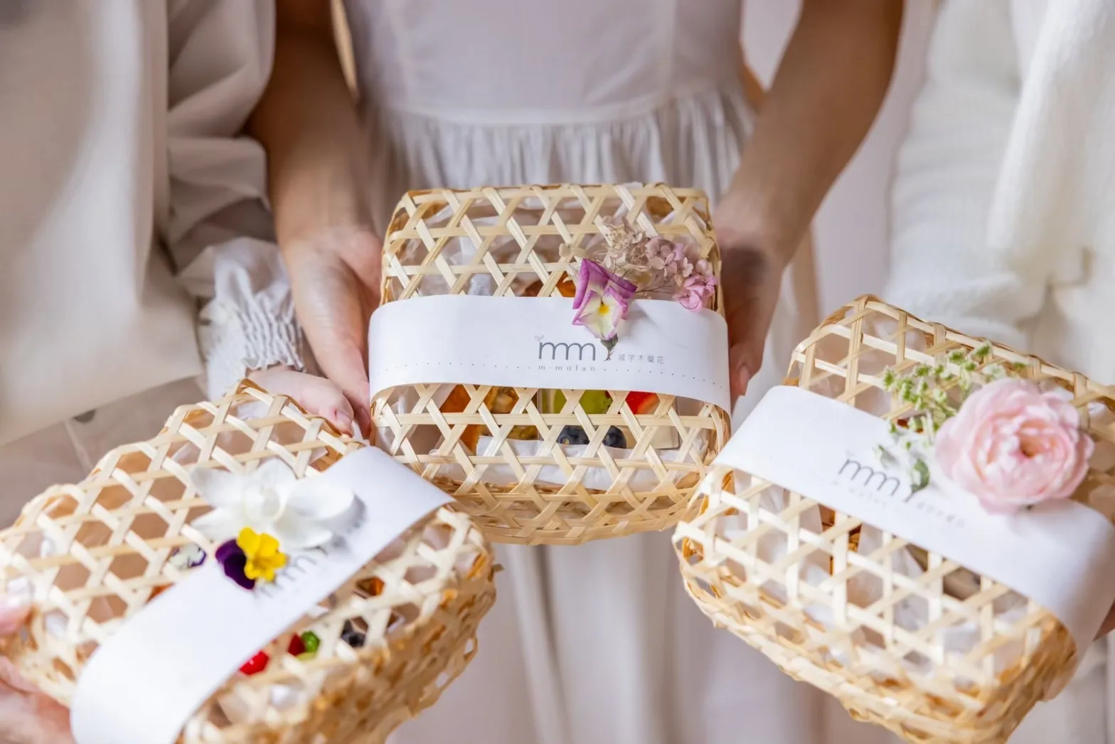 A trio of people holding M-Mulan tea sets